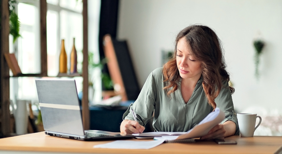 Cheffe de projet analysant des documents dans le cadre d’un audit en entreprise avec un ordinateur portable