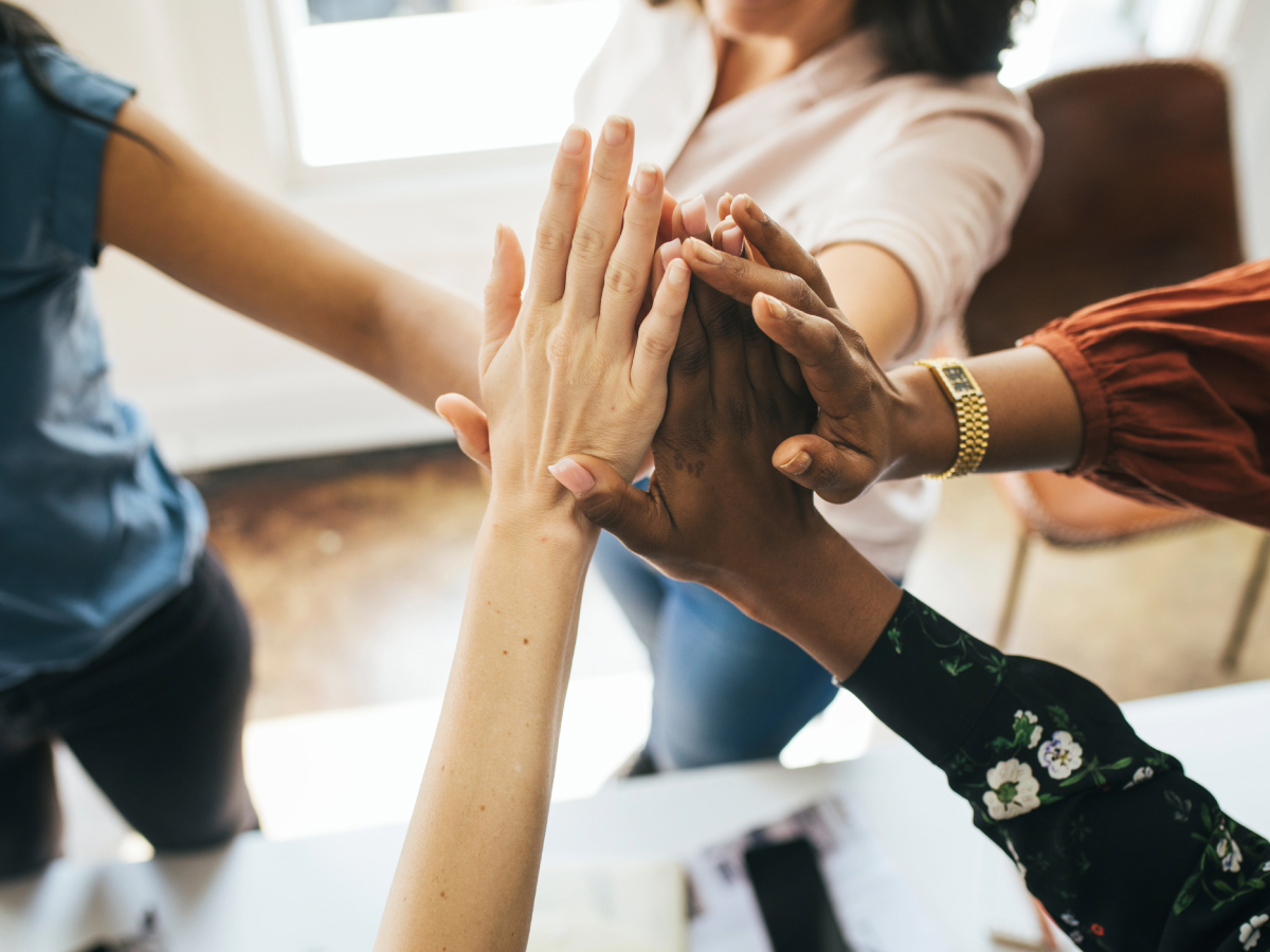 Plusieurs collègues de profils variés joignent leurs mains au-dessus d’une table, illustrant l’esprit d’équipe et la collaboration chez Incotec.