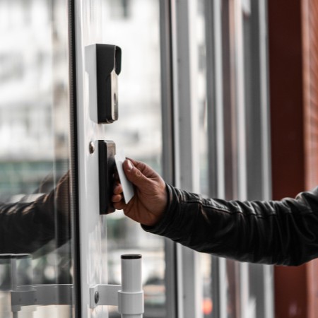 Contrôle d’accès par badge : une personne présente son badge d’accès devant un lecteur pour ouvrir une porte et sécuriser l’accès aux locaux grâce à un système de contrôle d’accès.