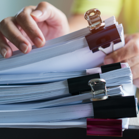 Mains triant une pile de dossiers RH, illustrant la gestion administrative du personnel dans un logiciel de gestion RH : suivi visite médicale, note de frais et gestion ticket restaurant.