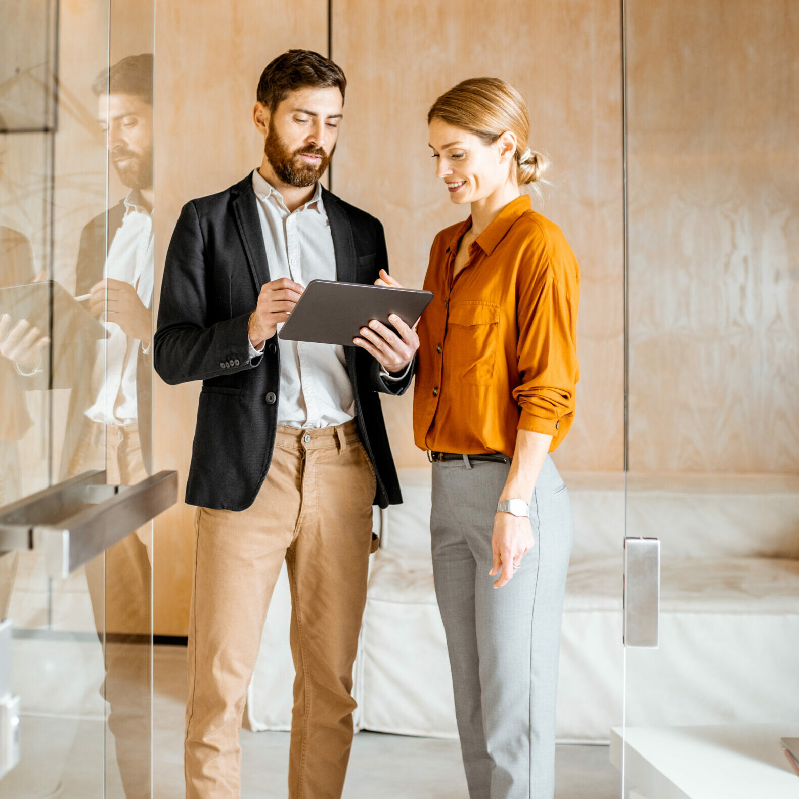 Deux professionnels, une femme et un homme, consultent une tablette dans un bureau pour analyser des indicateurs et échanger autour du reporting RH, à partir de données RH utiles au pilotage et au bilan social RH.